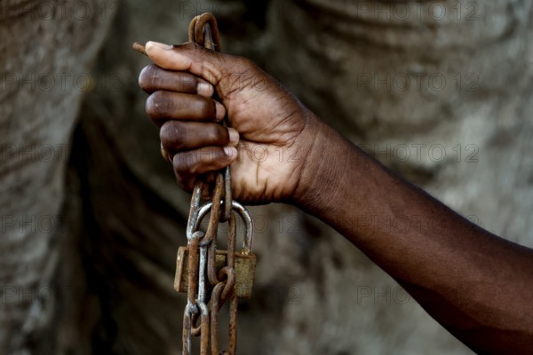 A hand firmly holds a heavy chain as a symbol of suffering, Bouaké, Ivory Coast