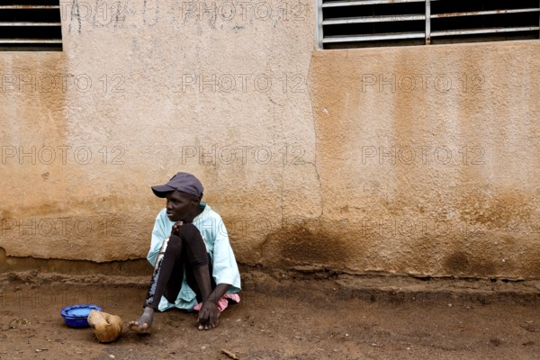 A patient sits alone with a plate against a wall, Bouaké, Nimbo, Côte d'Ivoire