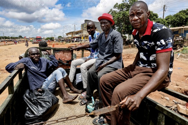 Group of men in a truck transporting a mentally ill homeless person to a psychiatric hospital, Bouaké, Côte d'Ivoire