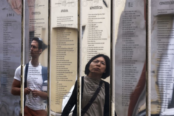 Passers-by look at the mirror installation with the Constitution of the Republic of Uzupis, Vilnius, Uzupis, Lithuania