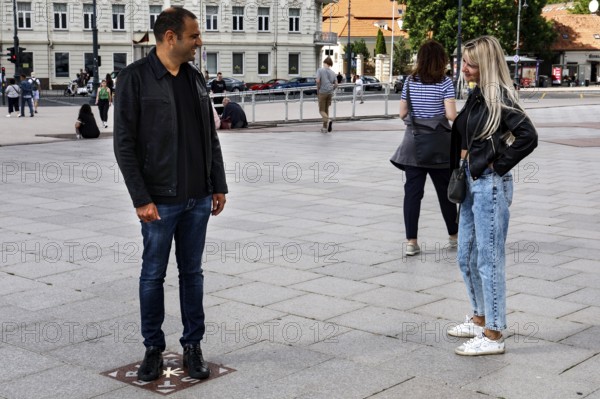 A couple talking on the miracle tile on Cathedral Square in Vilnius, Vilnius, Vilnius County, Lithuania