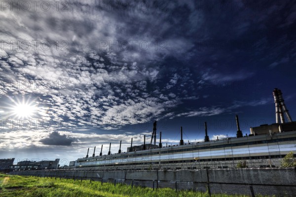 View of a disused power plant under a cloudy sky with sun, Visaginas, Lithuania