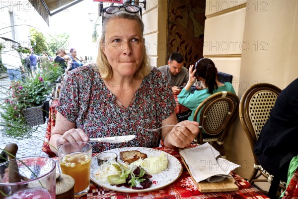A woman enjoying a meal at Etno Dvaras restaurant in Vilnius on a summer day, Vilnius, Vilnius County, Lithuania