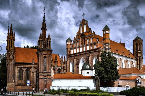 Gothic churches in Vilnius with dominant brick towers and dramatic cloudy sky, Vilnius, Lithuania