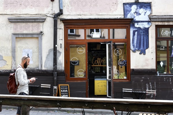 Passerby walks past a cafe in Uzupis, Vilnius, mural in the background, Vilnius, Vilnius County, Lithuania