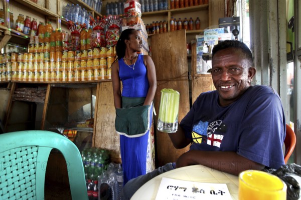 Man holding drink in colorful juice bar in Bahirdar, cheerful atmosphere, Bahirdar, Ethiopia
