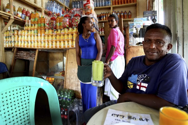 Man enjoying a drink in a cozy juice bar surrounded by laughter, Bahirdar, Ethiopia