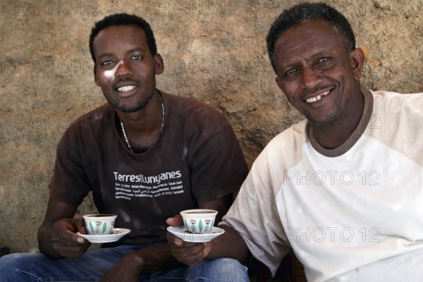 Bezhabe and Kusay take part in a relaxed coffee ceremony in Axum and hold coffee cups, Axum, Tigray, Ethiopia