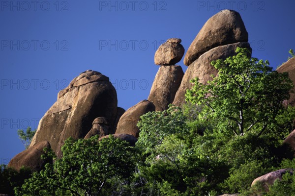 Steeply rising rocks surrounded by lush vegetation under bright blue skies, Babile, Oromia, Ethiopia