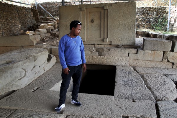 Guide Raphael shows ancient ruins in Axum's Stelenpark, known as Tomb of the False Door, Axum, Tigray, Ethiopia