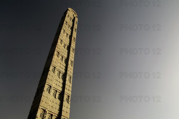 A tall, impressive stele rises majestically against the clear sky, Axum, Tigray, Ethiopia