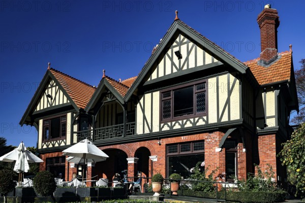 Historic Tudor style building with red bricks under blue sky in Mona Vale, Christchurch, Mona Vale, New Zealand