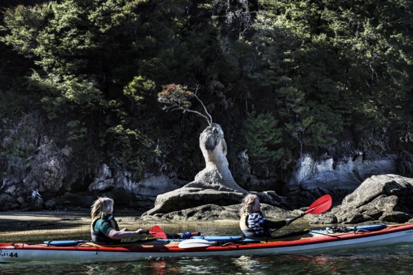 Two people kayaking in front of a rock formation on the water, Appletree Bay, Abel Tasman National Park, New Zealand