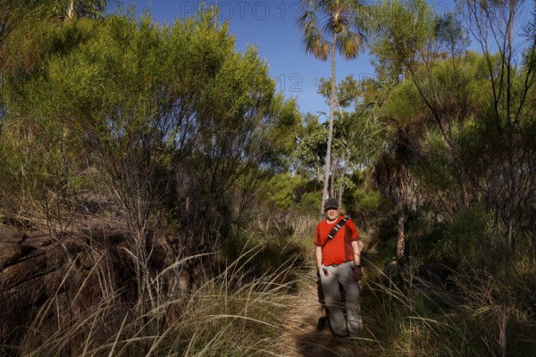 Man wearing red clothing wanders through dense landscape in Nitmiluk National Park, Nitmiluk National Park, Northern Territory, Australia