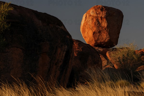 Balancing boulder in the desert, dramatically illuminated by the evening sun, Devil's Marbles, Northern Territory, Australia