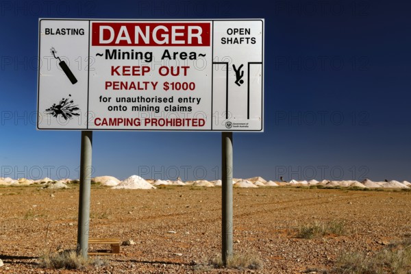 Warning sign of an opal mine in Coober Pedy with safety instructions in an arid desert landscape, Coober Pedy, South Australia, Australia