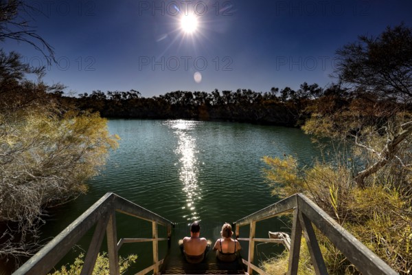 People relax at night at Dalhousie Springs under a starry sky, zero