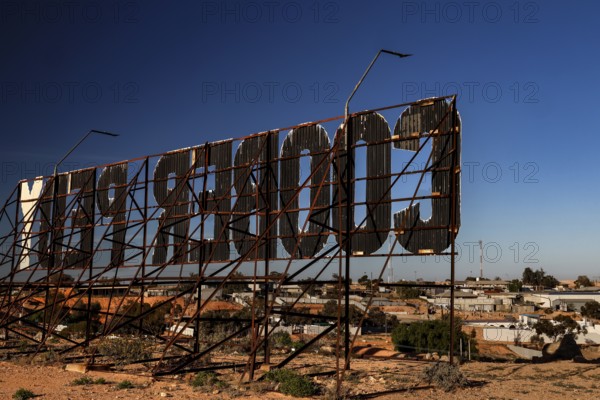 Metal structure sign in Coober Pedy shows the city name in a desert setting, Coober Pedy, South Australia, Australia