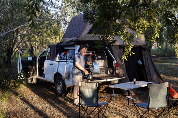 Forest campsite with a car tent and camping equipment in the evening light, Burdulba, Kakadu National Park, Australian Northern Territory