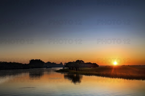 A clear sunrise is reflected in the water in Kakadu National Park, Kakadu National Park, Northern Territory, Australia