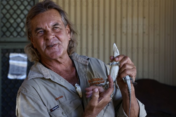 A man presents a baby crocodile in Malcolm Douglas Crocodile Park, Broome, Western Australia, Australia