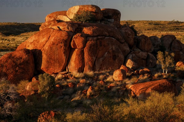 Large rock formation with surrounding vegetation in the Australian outback in sunlight, zero