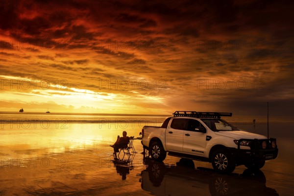 Sunset on Cable Beach with car, dog and sailboat in the distance, Broome, Western Australia, Australia