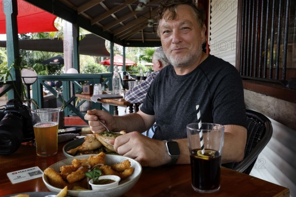Man enjoying a meal and drinks on the terrace of Matso's Broome Brewery, Broome, Western Australia, Australia