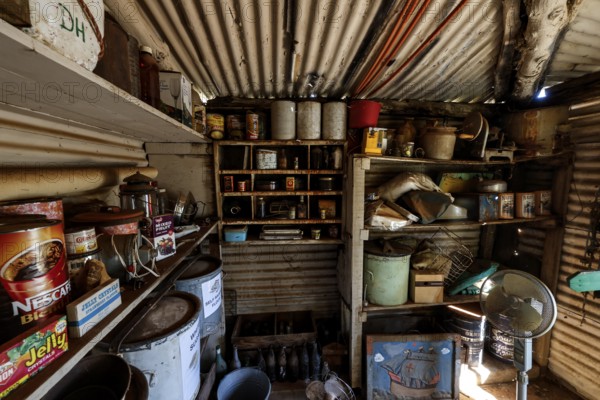 Pantry full of old tin cans and shelves under metal walls, zero