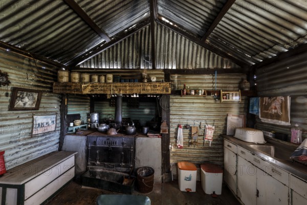 Rustic kitchen with old stove and tin walls, decorated with photos, zero