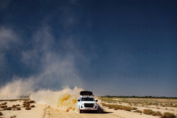 Four-wheel drive vehicle whirls up dust on desert road
