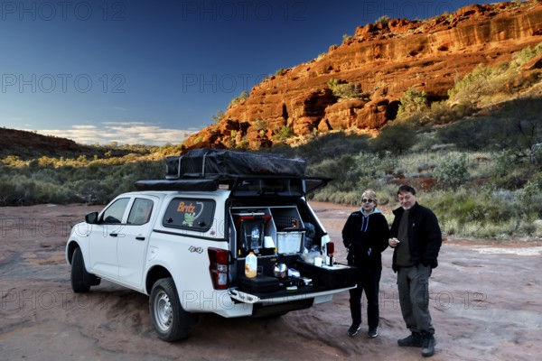 Off-road vehicle having breakfast break in front of impressive rocky backdrop in morning light, Palm Valley, Northern Territory, Australia