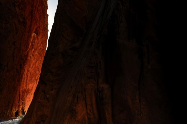Sunlight falls on the red rocks of Standley Chasm in a dramatic scene, Standley Chasm, Northern Territory, Australia