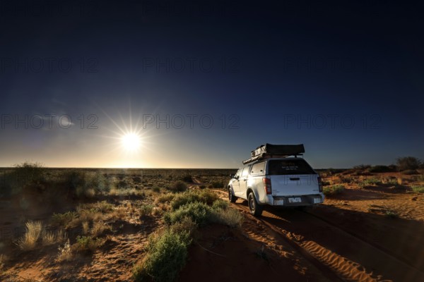 Off-road vehicle on sandy track in Simpson Desert, illuminated by sunrise, Simpson Desert, Northern Territory, Australia