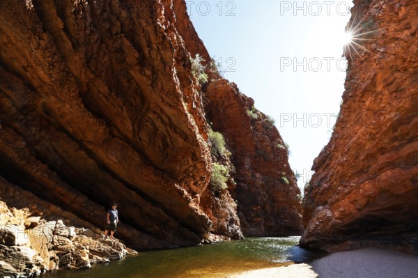 Narrow canyon of red rock with water and rays of sunlight, Simpson Gap, Northern Territory, Australia