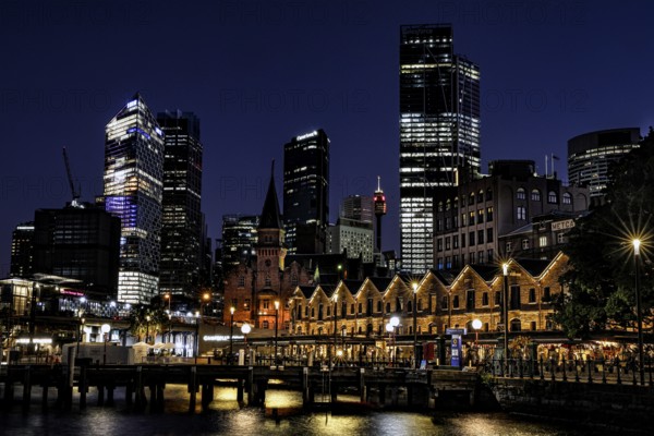 Night view of The Rocks in Sydney with illuminated former warehouses and modern skyscrapers, Sydney, NSW, Australia