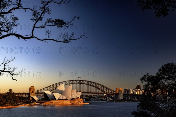 Sydney Opera House and Harbour Bridge at sunrise against blue sky, Sydney, New South Wales, Australia