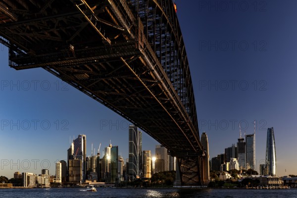Sydney's skyline at dusk under the massive Harbour Bridge, Sydney, New South Wales, Australia