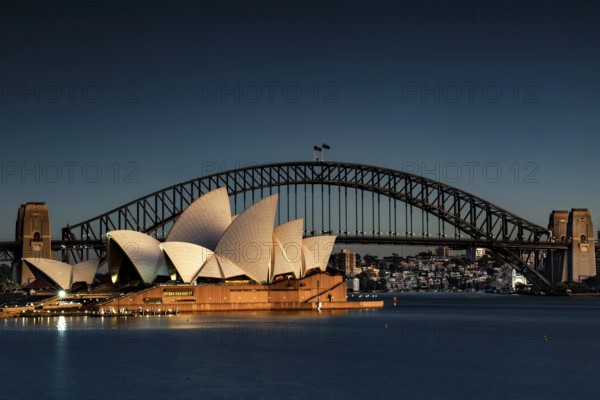 Illuminated opera house and harbour bridge in front of the night skyline of Sydney, Sydney, New South Wales, Australia