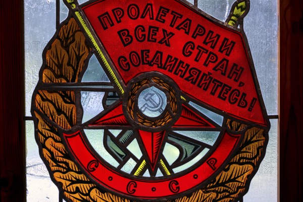 Socialist coat of arms with red banners and symbols in a stained glass window in Grutas Park, Druskininkai, Lithuania