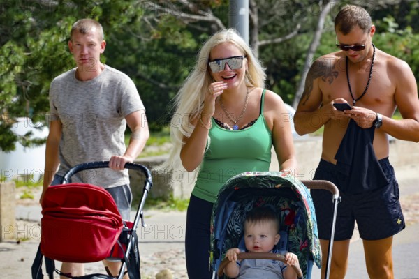 A family with stroller strolls along the promenade, Pärnu, Estonia on a sunny day