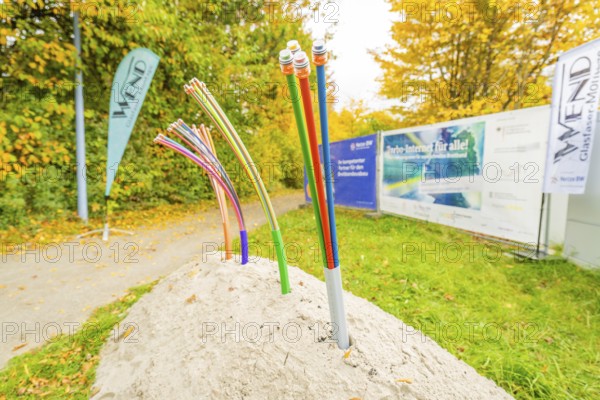 Colorful fiber optic cables sticking out of a pile of soil on a green area, fiberglass groundbreaking, Dornstetten, Freudenstadt, Germany
