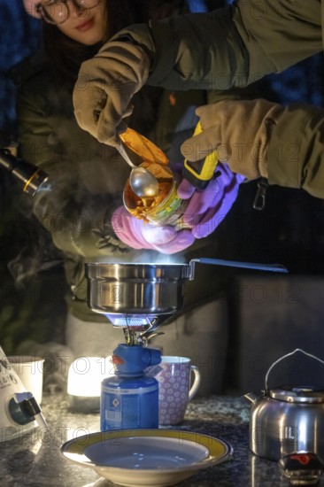 Symbolic picture blackout, extensive, prolonged power failure, in private surroundings, without electricity, heating, water, cooking, heating food and water with a gas-powered camping stove, on the balcony