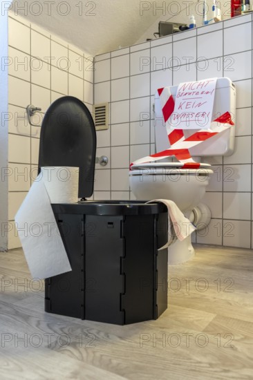 Symbolic picture blackout, extensive, prolonged power failure, in private environments, without electricity, the water supply also fails, toilet flush no longer works, emergency toilet, mobile toilet, camping toilet as an emergency replacement, disposal in bags