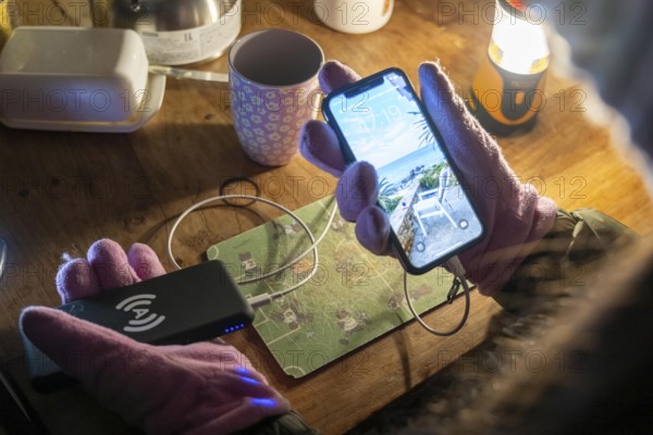 Symbolic picture blackout, extensive, prolonged power failure, in private surroundings, without electricity, heating, water, mobile phone is charged with a power bank