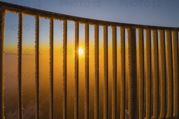 Sunset behind an icy railing with orange sky in the Teutoburg Forest on the Steinegge observation tower, Dissen, Osnabrücker Land, Teutoburg Forest, Lower Saxony, Germany