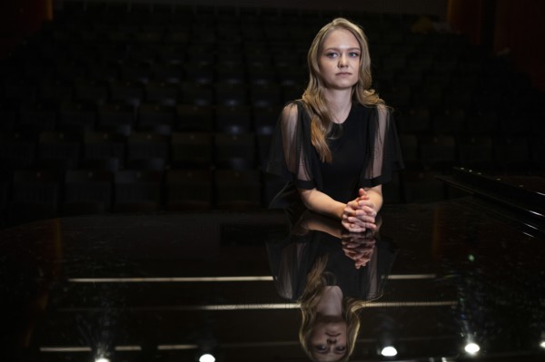 Young woman, pianist, in evening dress, with folded hands supported on Steinway & Sons grand piano, Stuttgart, Baden-Württemberg, Germany