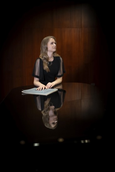 Young woman, pianist, with notes by Johann Sebastian Bach in concert hall, supported on Steinway & Sons grand piano, Stuttgart, Baden-Württemberg, Germany