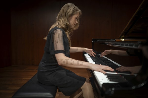 Young woman, pianist, side view playing on a Steinway & Sons grand piano in evening dress, Stuttgart, Baden-Württemberg, Germany