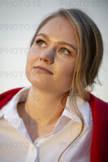 Portrait of a thought-looking young woman, pianist, wearing white blouse and red cardigan, in the evening light, Stuttgart, Baden-Württemberg, Germany